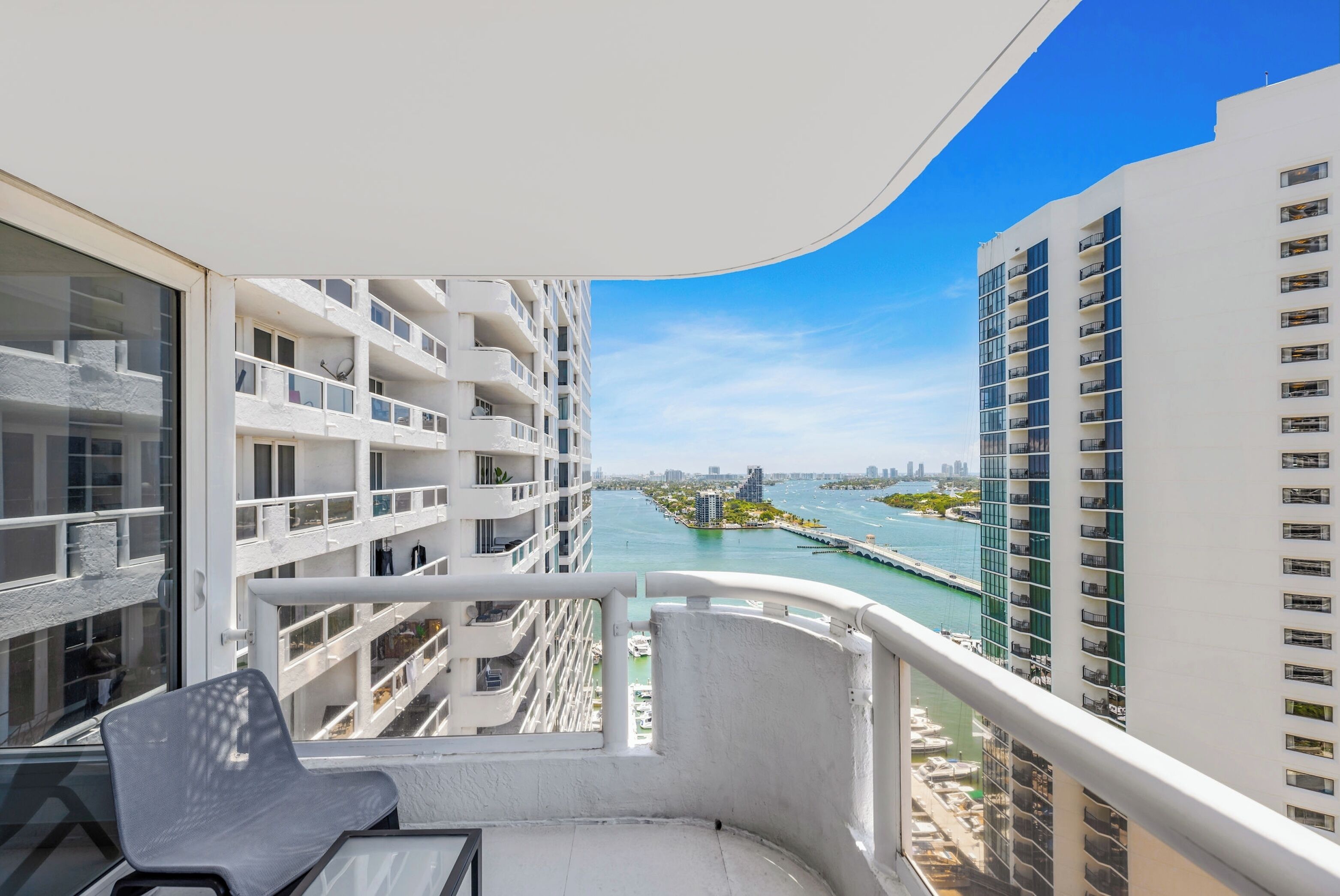 A balcony with a view of a marina and high-rise buildings.