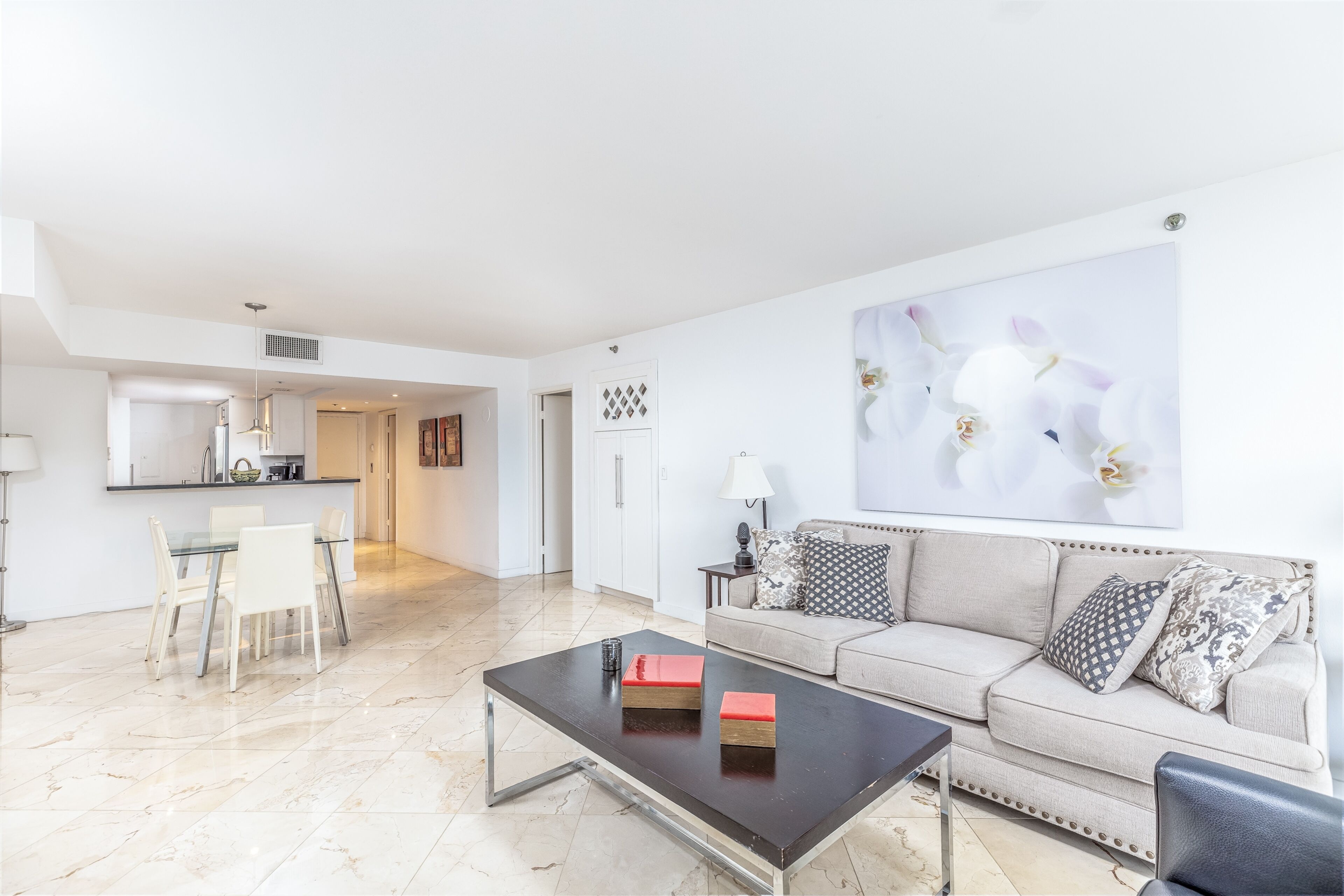 A modern living room with a sofa, a coffee table, and a dining area with chairs.