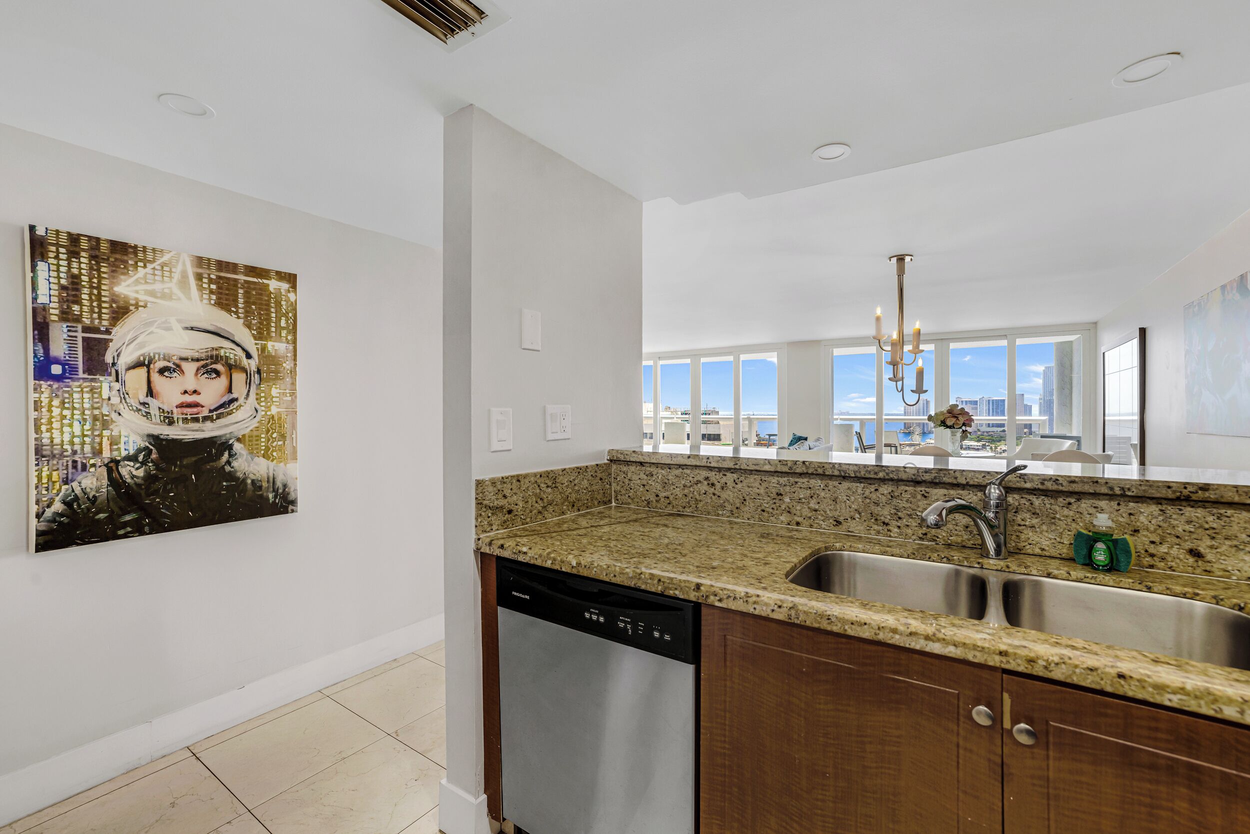 A modern kitchen with granite countertops, stainless steel sink, and a dishwasher.