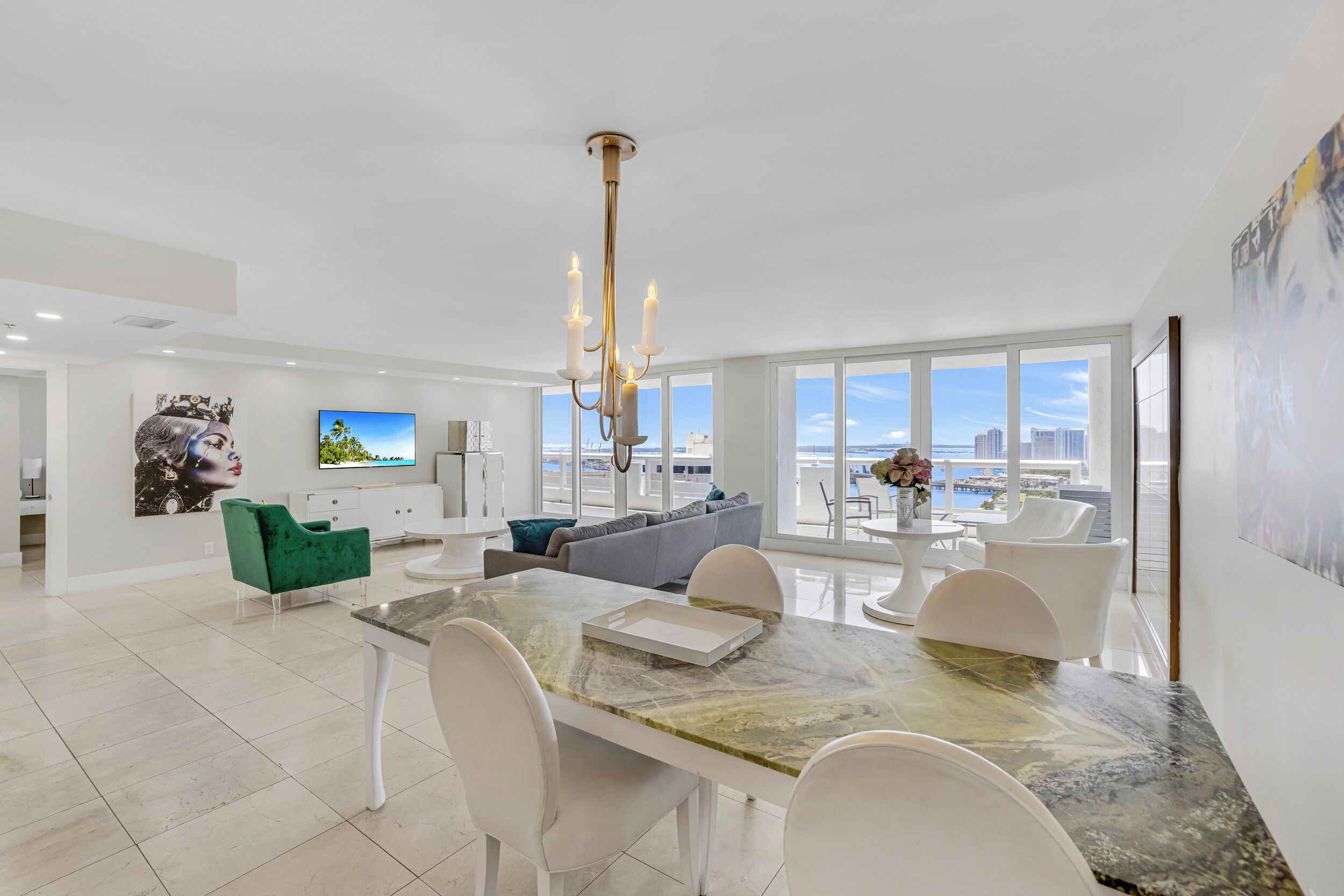 A modern living room with a dining area, large windows, and a view of the cityscape.