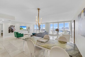 A modern living room with a dining area, large windows, and a view of the cityscape. - Comfort, Space and Perfect Sunset (Miami)