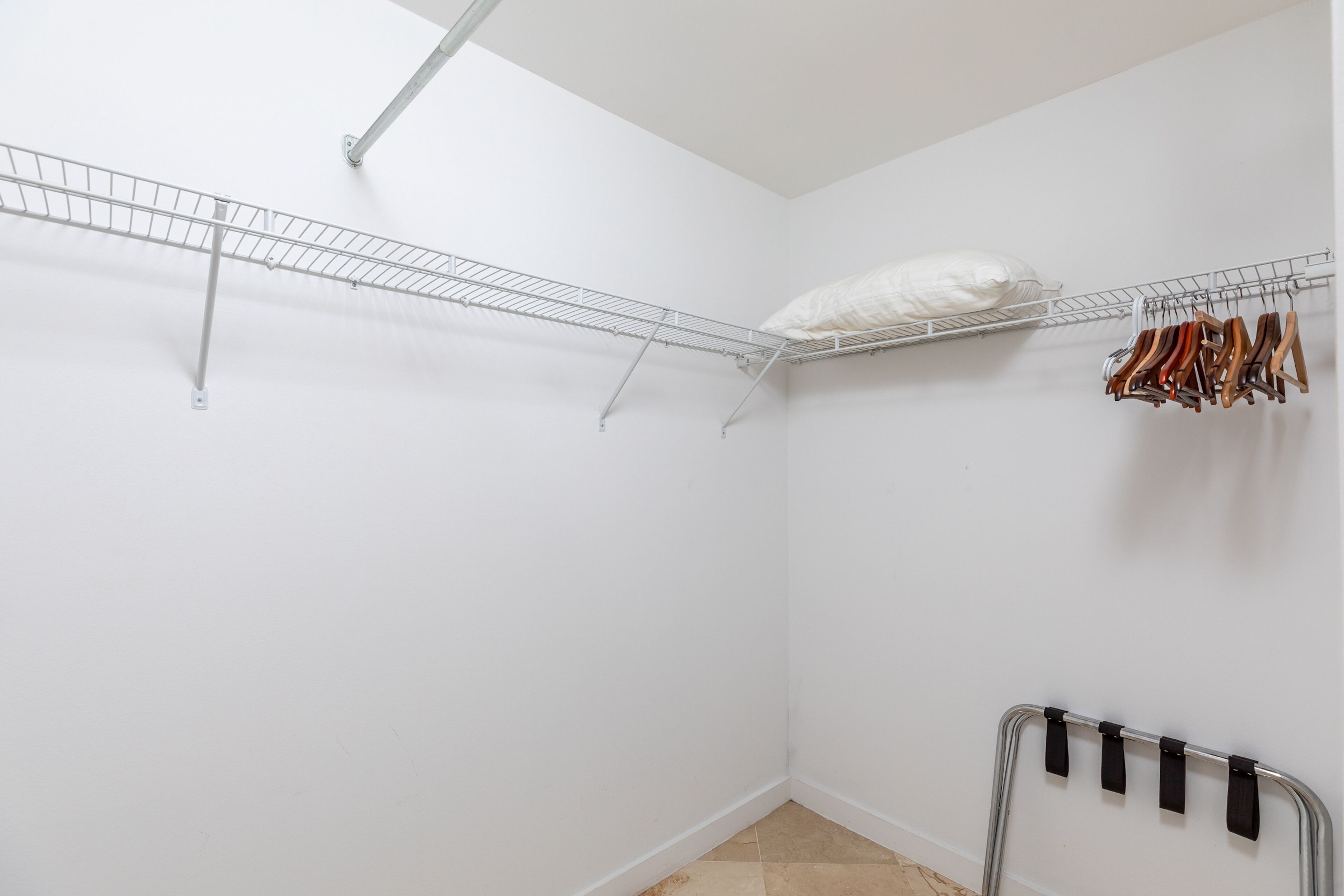 A white closet with metal shelves, a hanging rack, and a shoe rack.