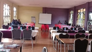 A conference room with tables and chairs, a whiteboard, and a projector screen. - Jambo Village Hotel (Murang'a)