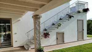 A modern building with a staircase, a balcony with flowers, and a door.