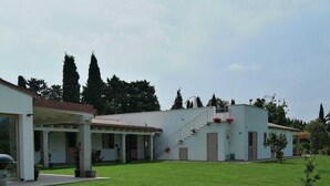 A white building with a covered patio and a grassy lawn.