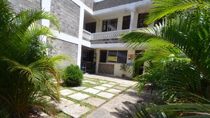 Un patio con senderos de piedra, palmeras y un edificio con balcón.