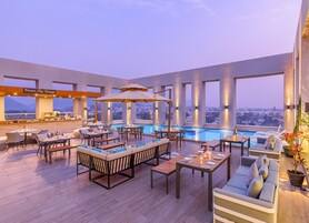 Un lounge en la azotea con piscina, mobiliario exterior y vistas a la ciudad.