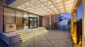 A modern building entrance with a glass door, a revolving door, and a staircase leading to the entrance.