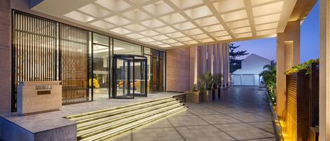 A modern building entrance with a glass door, a revolving door, and a staircase leading to the entrance.