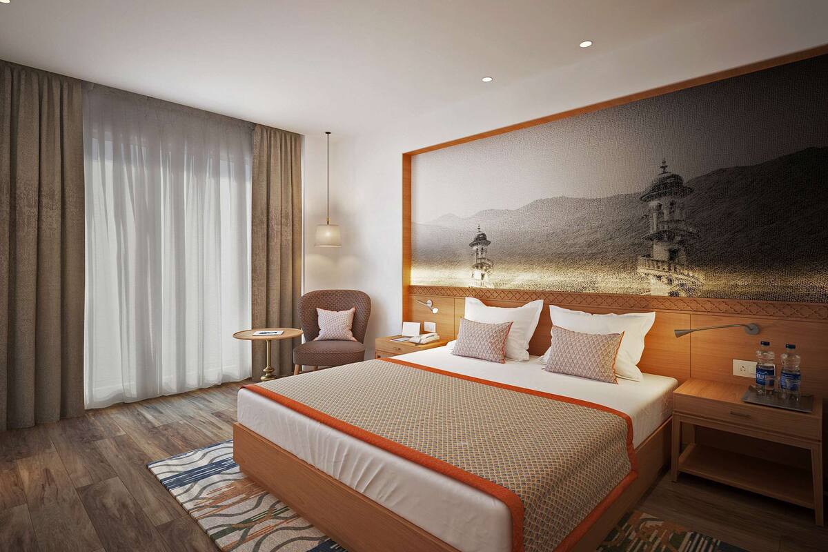 Ein Hotelzimmer mit einem großen Bett, einem Sessel, einem Nachttisch und einem Bild an der Wand.