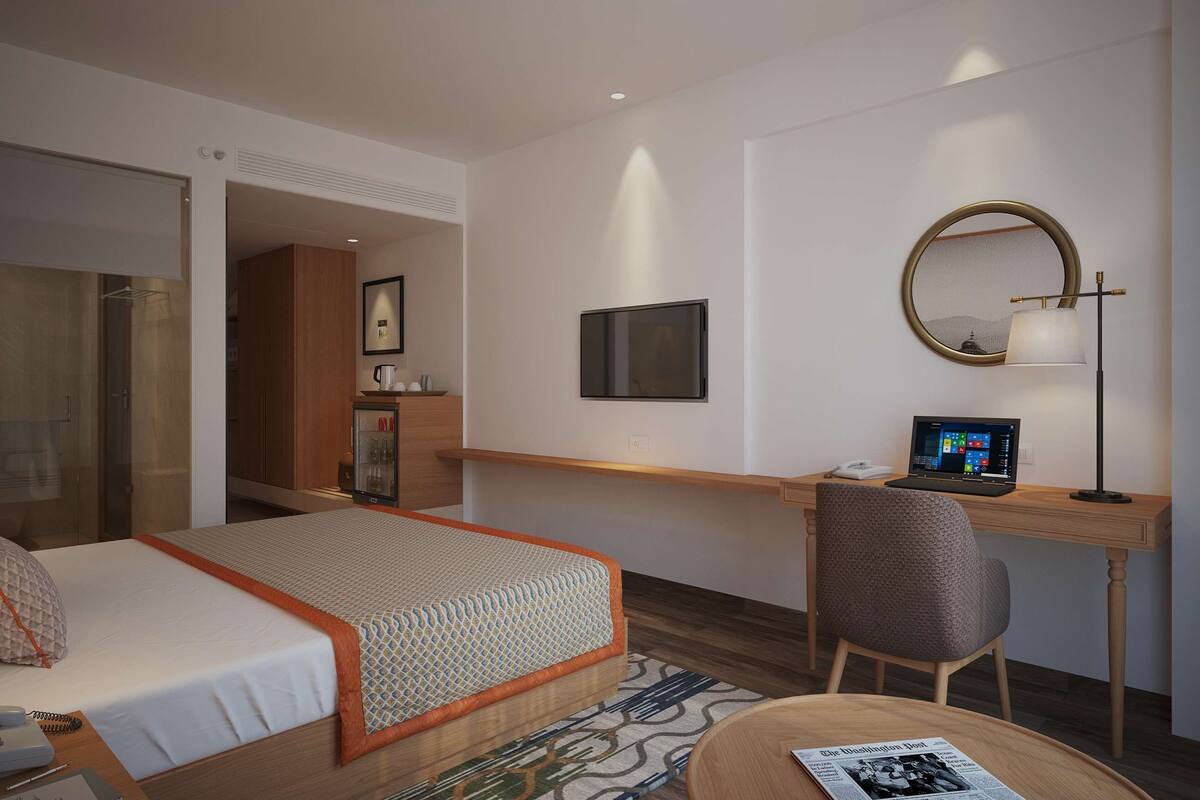 Ein Hotelzimmer mit Bett, Schreibtisch, Stuhl und Fernseher.