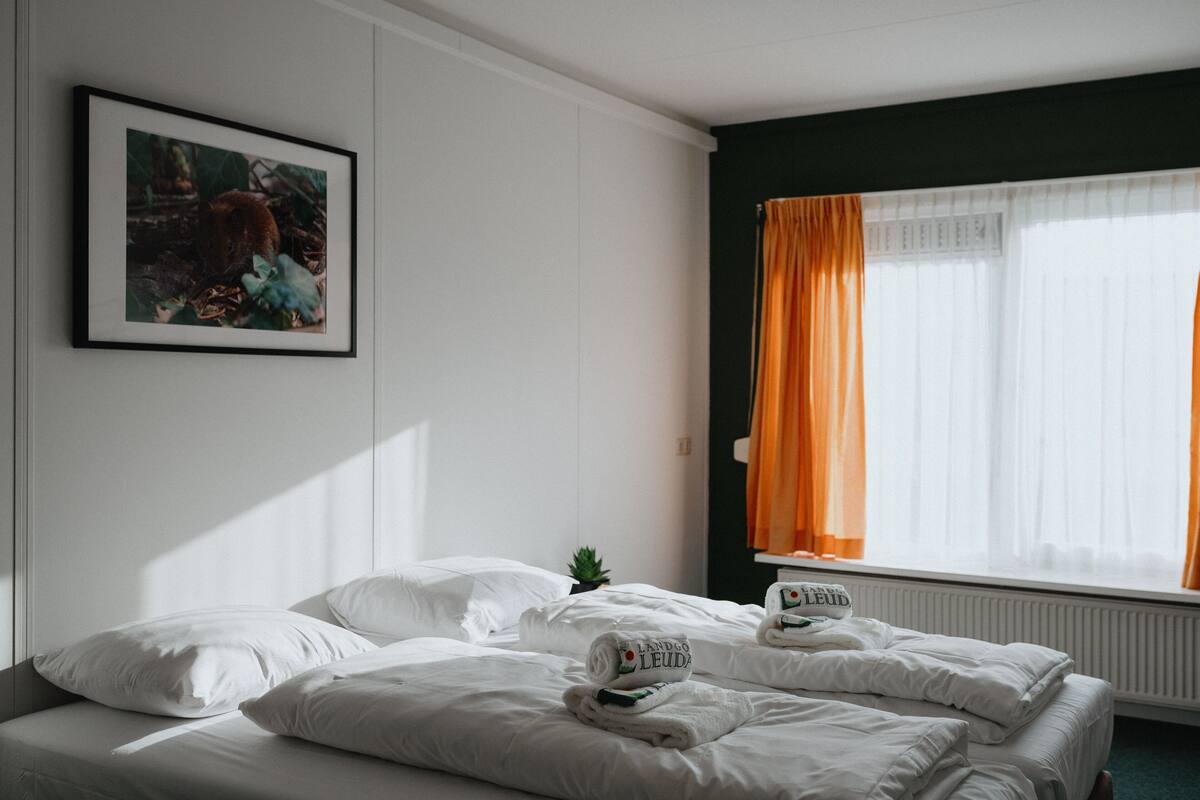 Una habitación de hotel con una cama bien hecha, un cuadro en la pared y una ventana con cortinas.