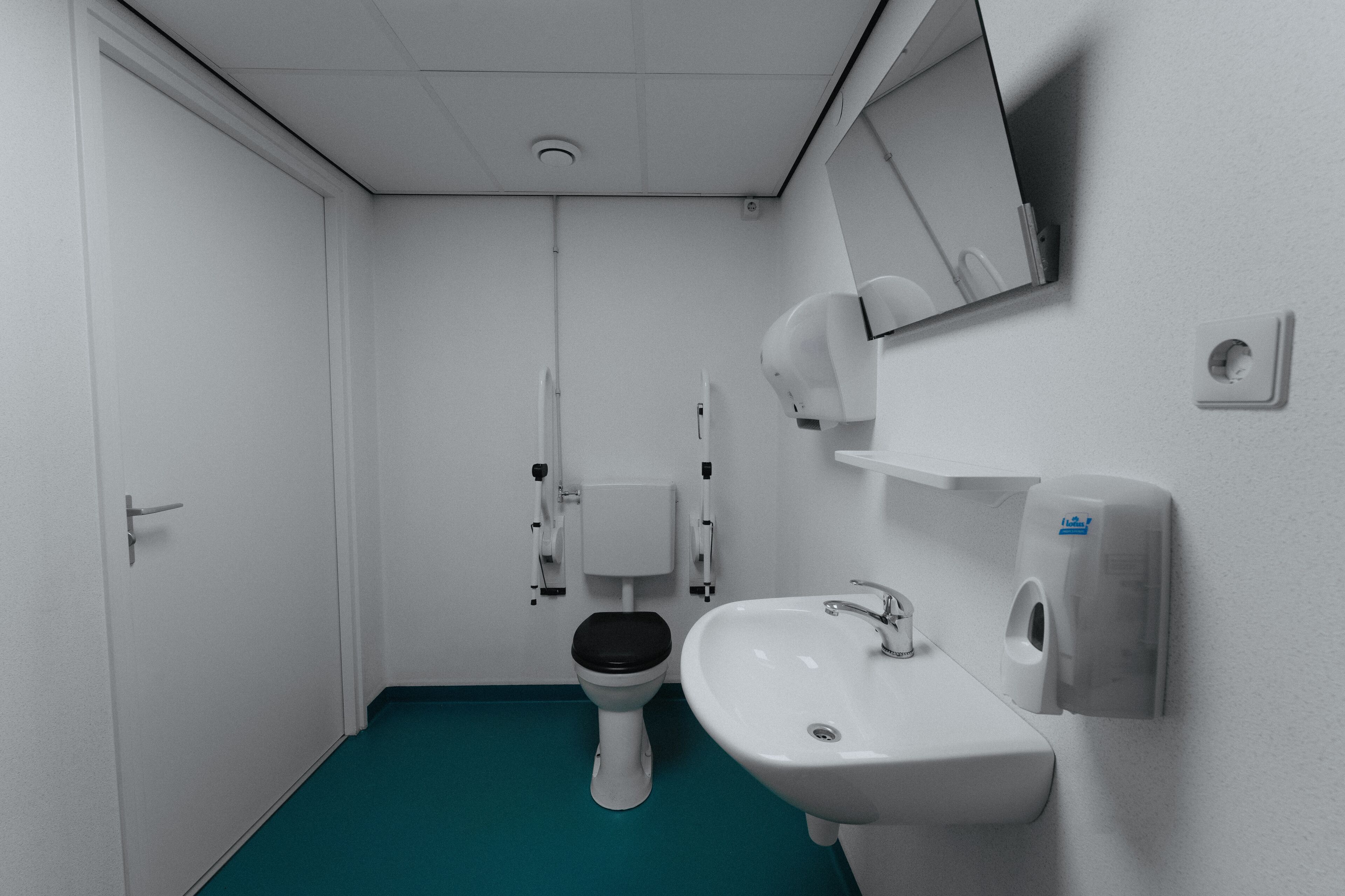 A small, clean bathroom with a toilet, sink, and hand dryer.