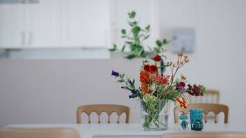 A dining table with a clear glass vase containing a variety of flowers.