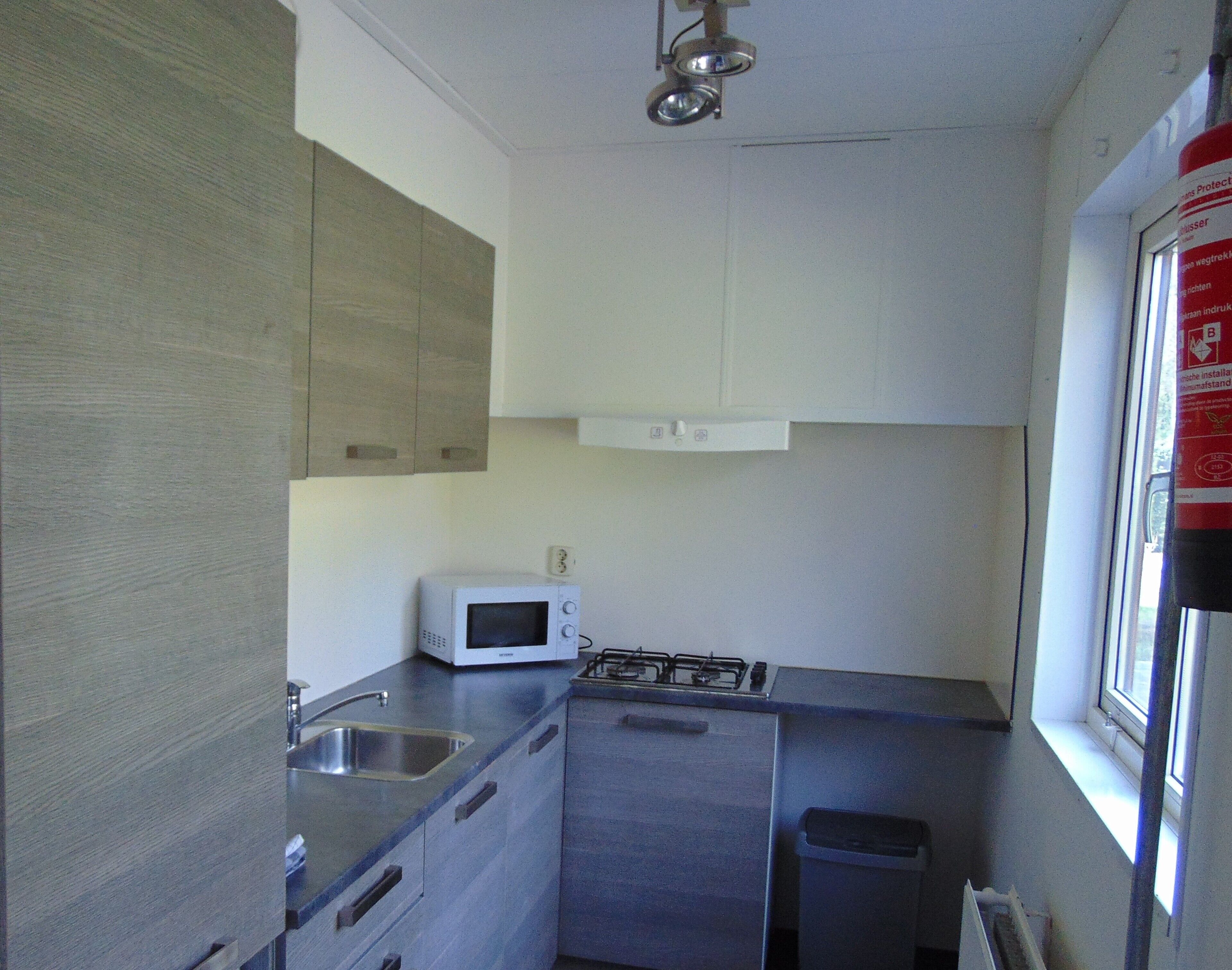 Uma cozinha compacta com micro-ondas, fogão a gás e pia.