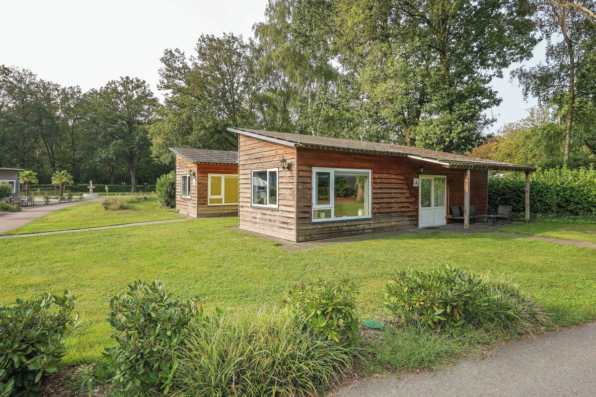 A small wooden cabin with a porch and a lawn in front.