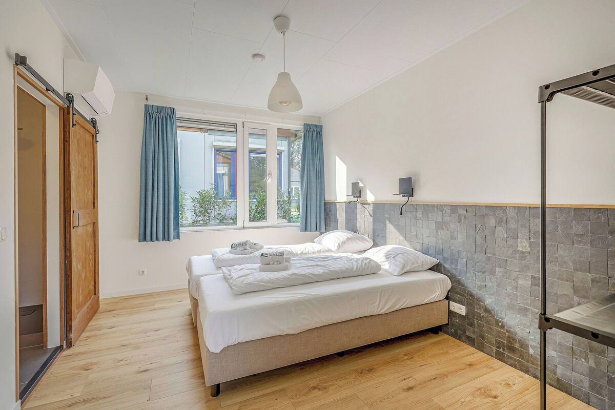 Un dormitorio con cama, armario, ventana con cortinas y estante en la pared.