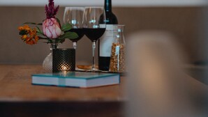 A table with a vase of flowers, a wine bottle, glasses, and a jar of nuts. - Landgoed Leudal (Haelen)