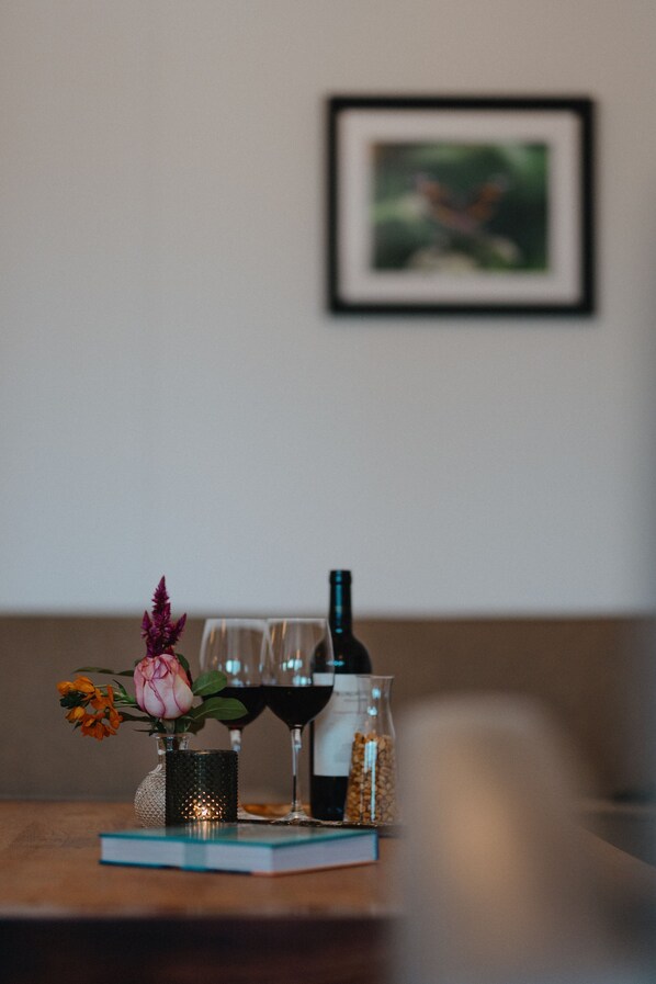 A table with a vase of flowers, a wine bottle, glasses, and a jar of nuts. - Landgoed Leudal (Haelen)
