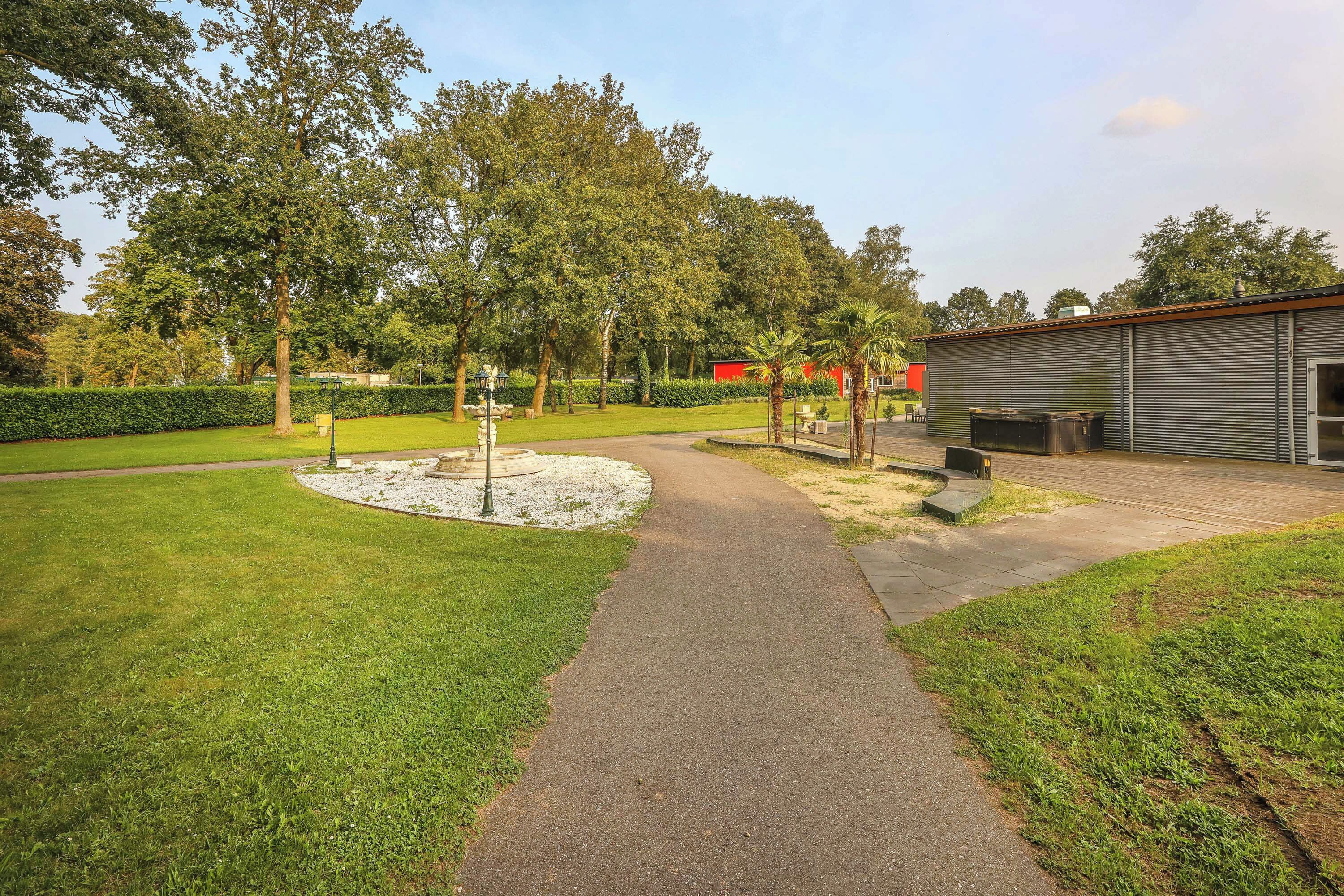 A pathway leading to a building with a red roof, surrounded by well-maintained grass and trees.