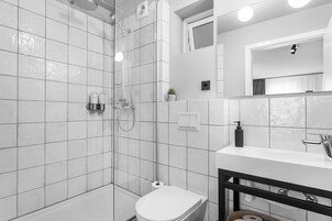 Un bagno moderno con doccia vetrata, un water bianco e un mobile lavabo nero con specchio.