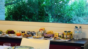 A dining table set with plates, cutlery, glasses, and condiments, with a view of lush greenery through a window. - B&B Beauty House (Cesena)