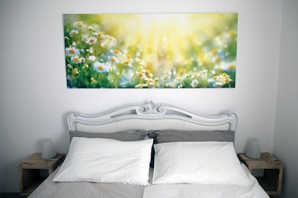 A bedroom with a white bed, two bedside tables, and a wall-mounted picture of flowers. - B&B Beauty House (Cesena)