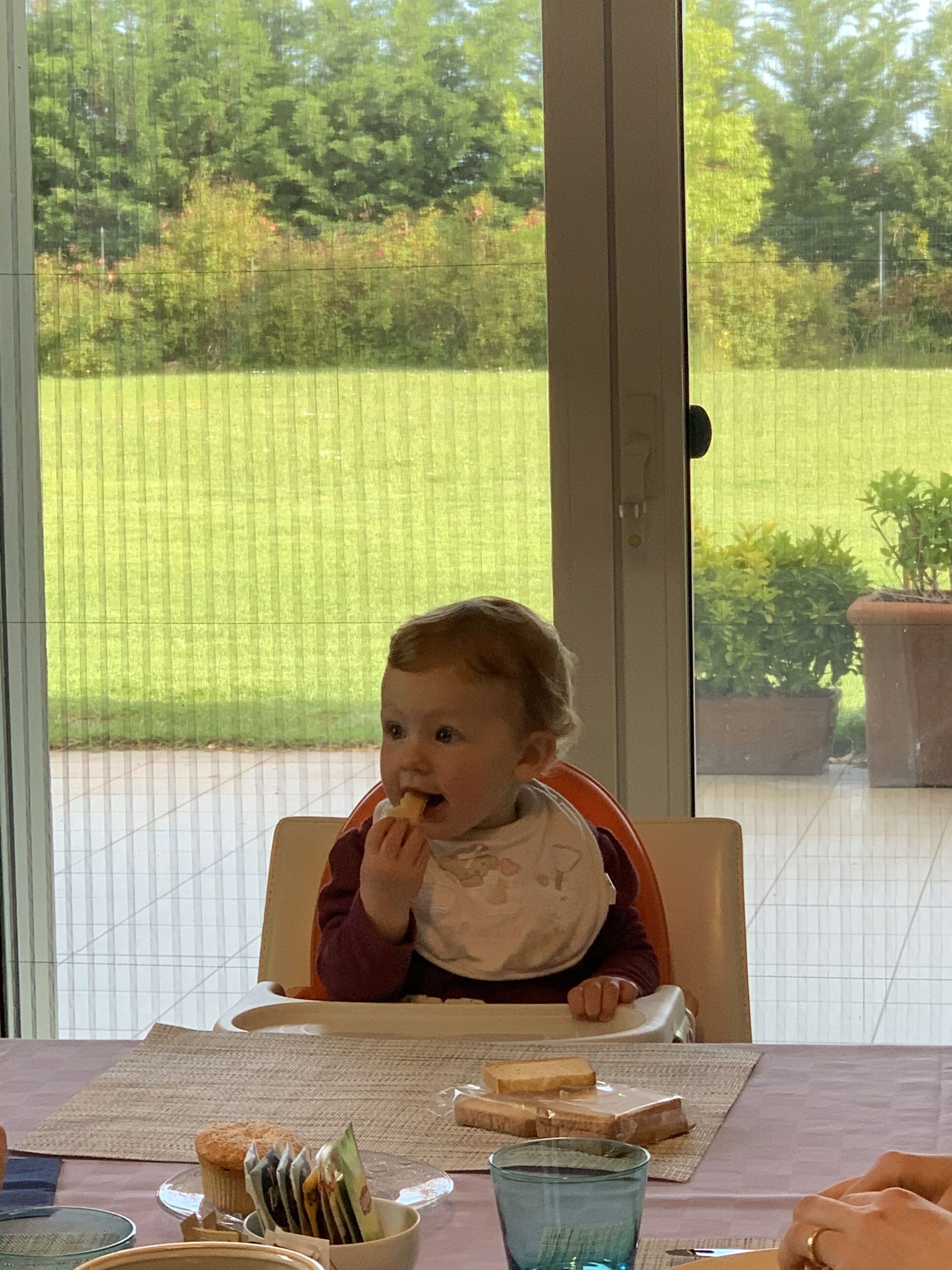 Un niño sentado a una mesa con comida, un vaso y un mantel individual.