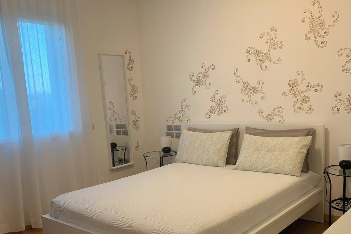 A bedroom with a bed, a bedside table, a mirror, and floral wall decals.