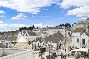Un pueblo histórico con edificios de piedra tradicionales, calles estrechas y una plaza central con mesas al aire libre.