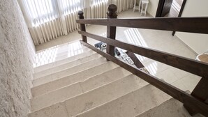 A staircase with a wooden handrail leading to a landing. There is a radiator on the landing, and a small table with a plant on it. - Perlage Suite Luxury B&B (Alberobello)