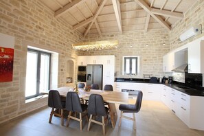 Une cuisine spacieuse avec des meubles blancs, un plan de travail noir et un luminaire suspendu.