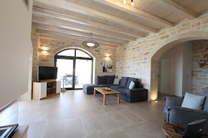 Un salon spacieux avec un mur en pierre, un téléviseur à écran plat, un canapé et une table basse.