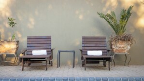 Deux fauteuils de jardin en bois, accompagnés de serviettes, une petite table et un pot de fleurs, le tout placé au bord de la piscine.