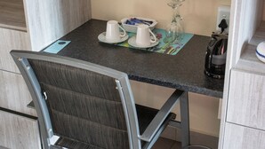 Une petite cuisine équipée d’une table, d’une chaise et d’une machine à café.