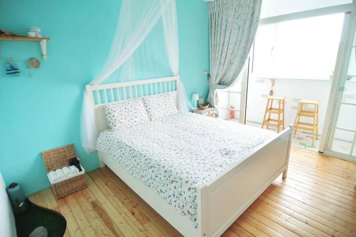 A bedroom with a bed, a wicker basket, and a wooden floor.