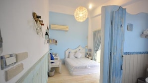 Une chambre à coucher comprenant un lit, des tables de chevet, un luminaire suspendu, ainsi qu’une salle de bain avec douche et toilettes.