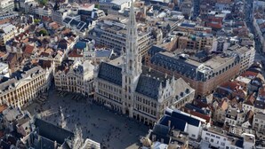 Una plaza histórica de la ciudad con un imponente edificio de estilo gótico que presenta una alta torre.