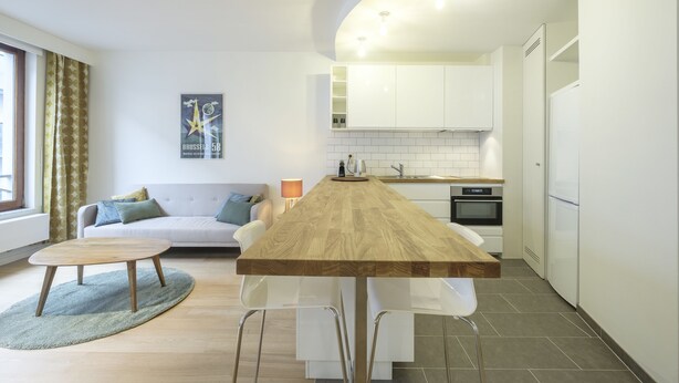 Una cocina moderna con una isla de madera, armarios blancos y un horno empotrado.