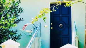 A front view of a house with a black door, a white gate, and a staircase leading to the entrance. - Casa FioRita (Vieste)