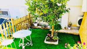 A small patio area with a white metal table and chairs, surrounded by a wooden fence. - Casa FioRita (Vieste)
