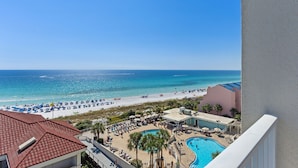 Une vue sur la plage depuis un balcon, avec une piscine et un espace de détente.