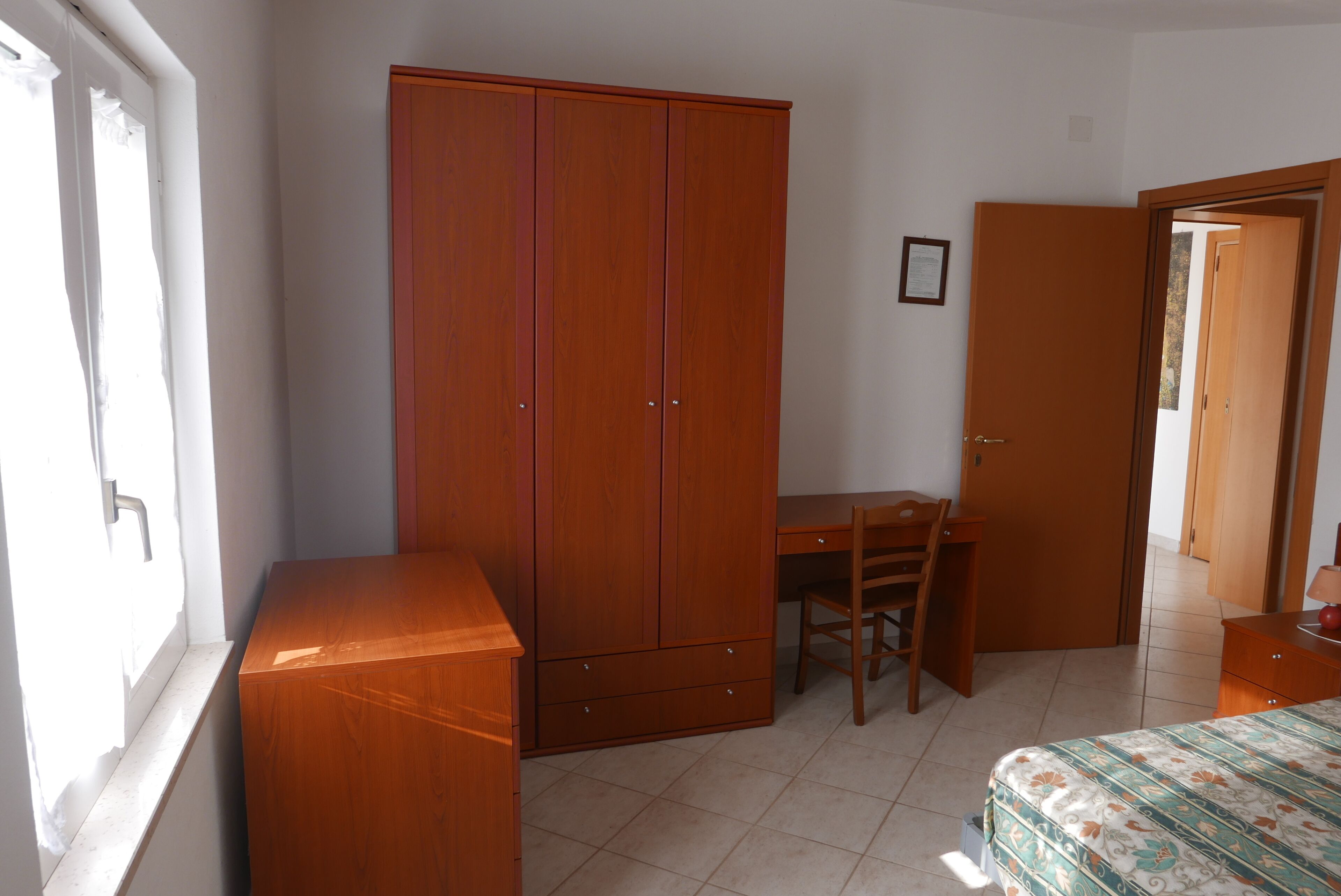 Ein Schlafzimmer mit einem Holzkasten, einem Schreibtisch und einem Bett.