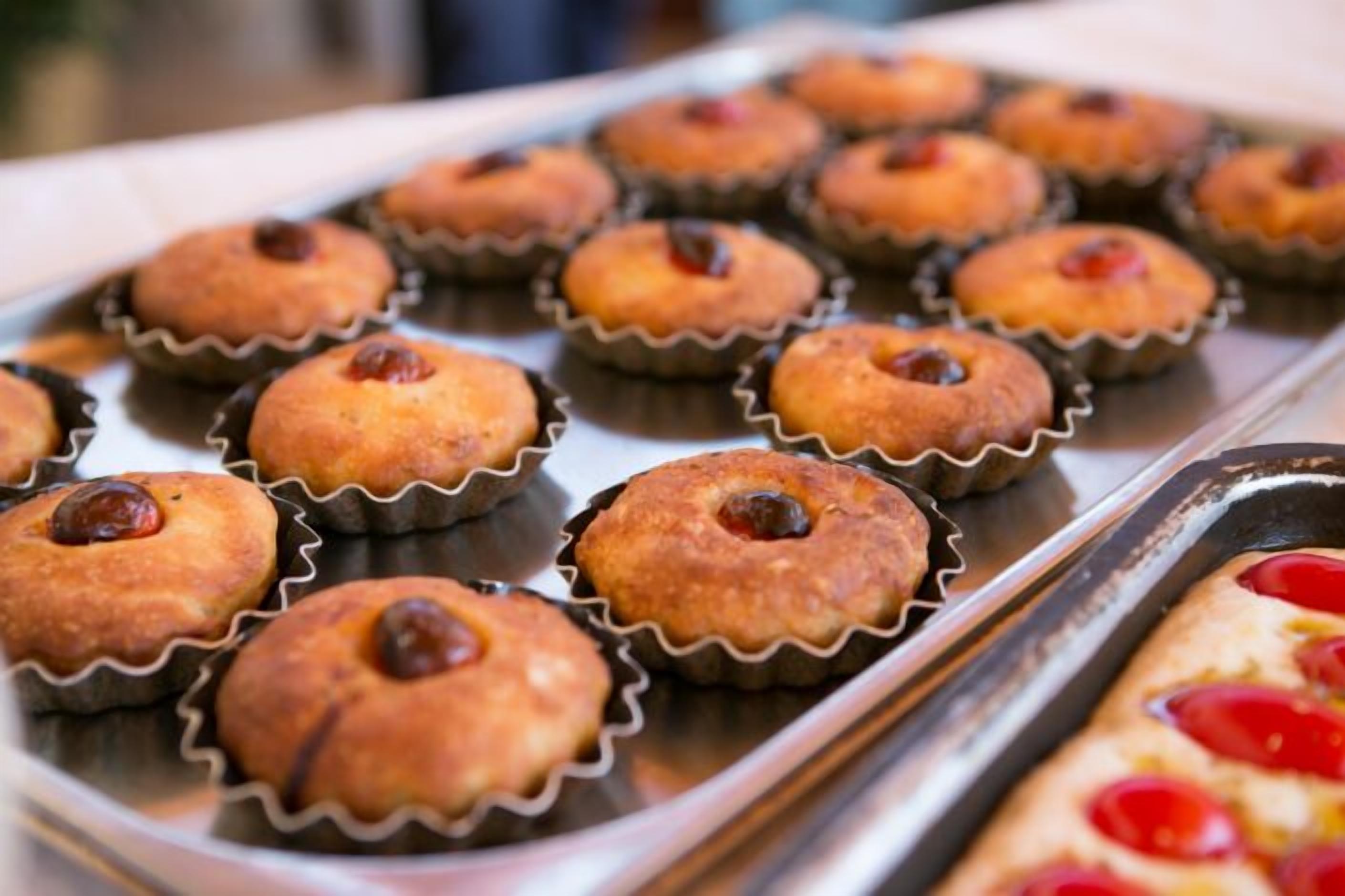 Eine Tablett mit Muffins, jedes mit einer Kirsche belegt.