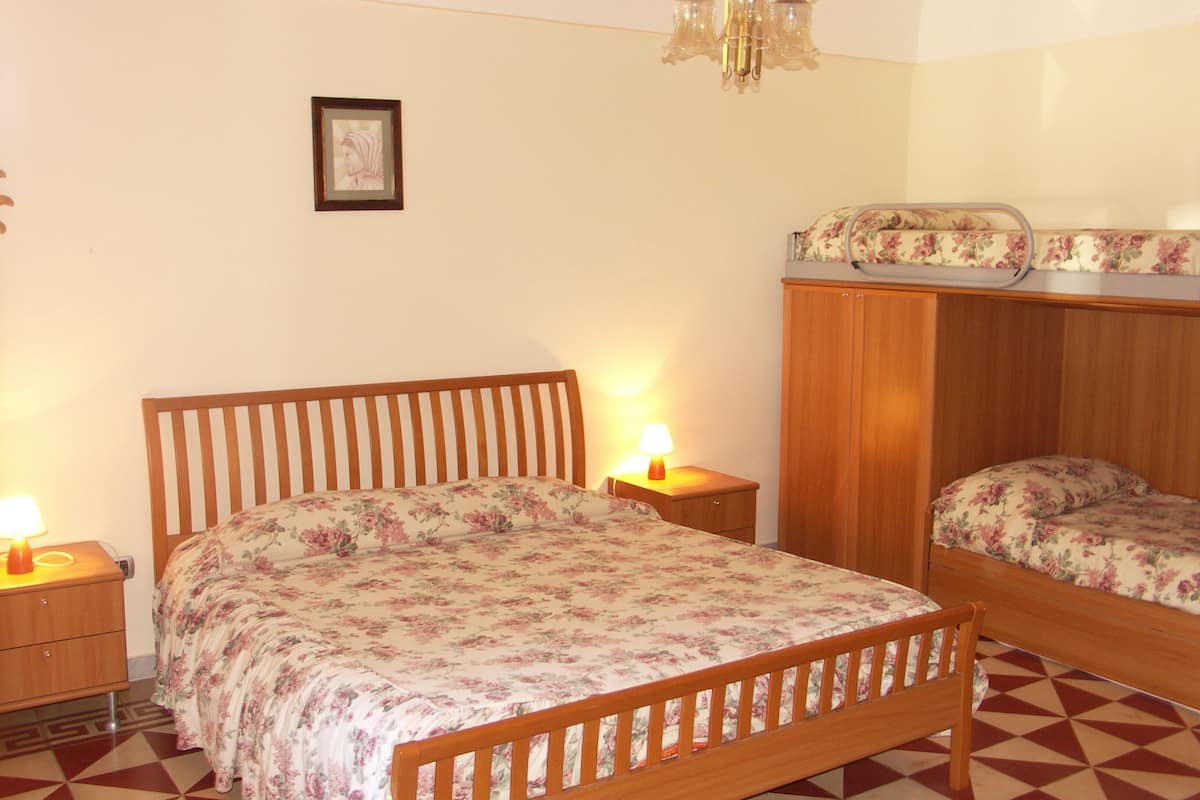 A bedroom with a wooden bed, a nightstand, a dresser, and a chandelier.