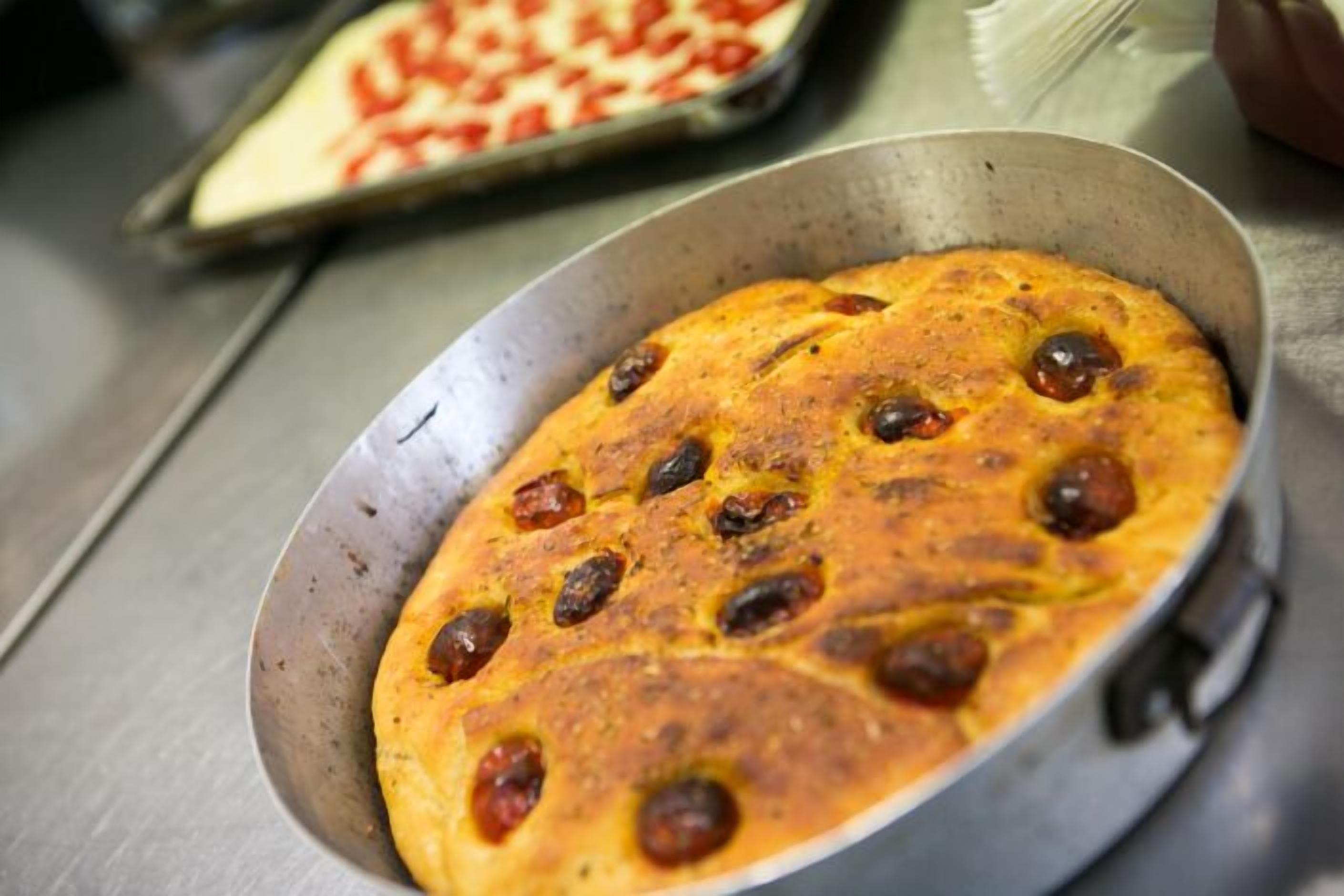 A round, baked dish with visible olives in a metal pan.