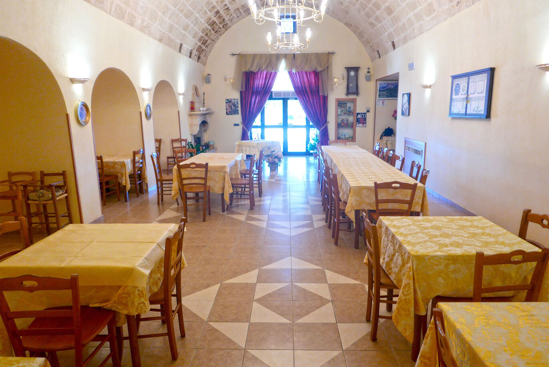 Un comedor con varias mesas y sillas, un piso con diseño y vistas al exterior a través de ventanas amplias.