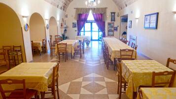 Un comedor con varias mesas y sillas, un piso con diseño y vistas al exterior a través de ventanas amplias.