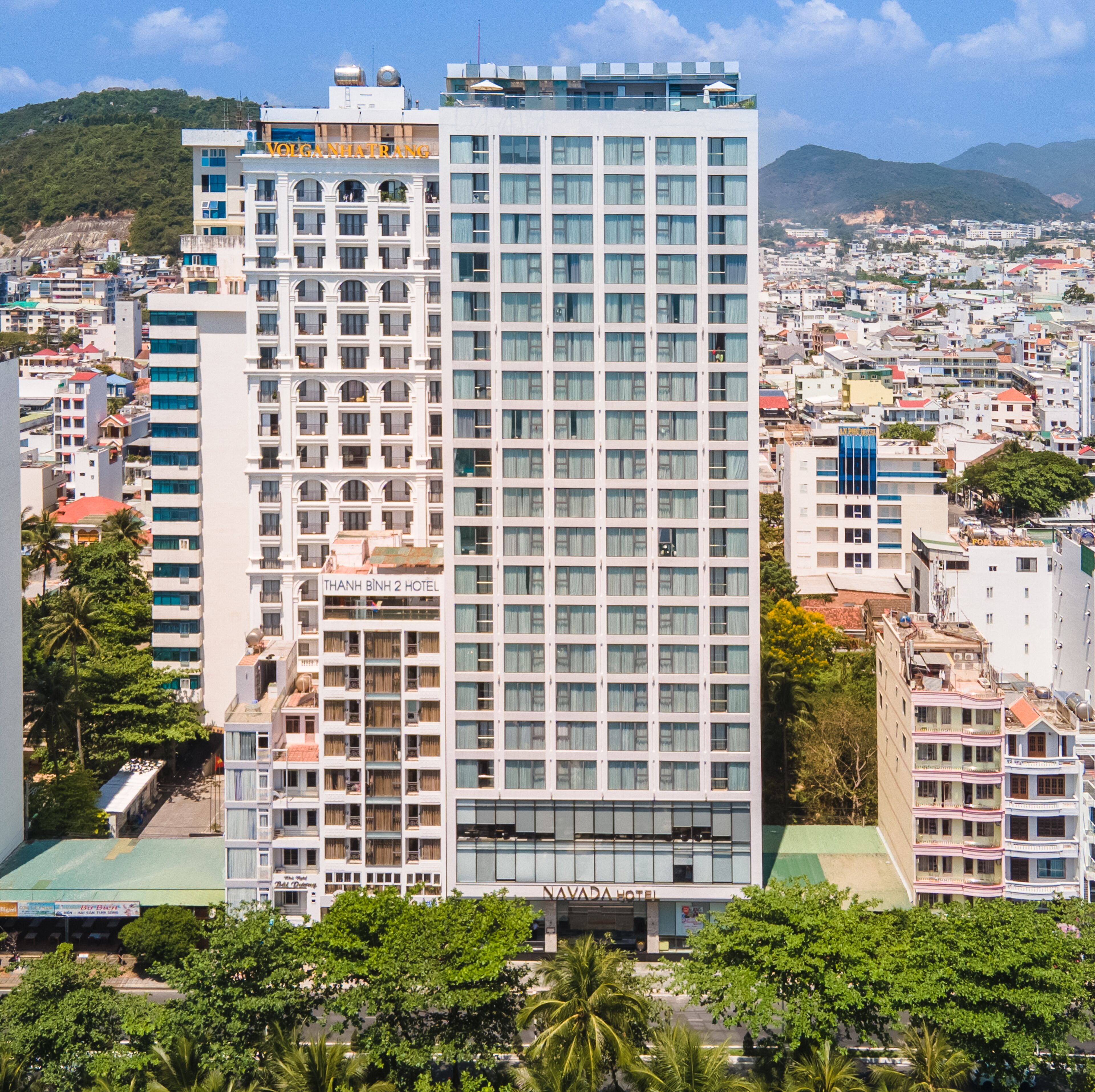 A multi-story hotel with a modern facade, balconies, and a view of the surrounding cityscape.