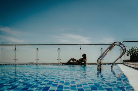 Una piscina al aire libre, una piscina infinita, sombrillas